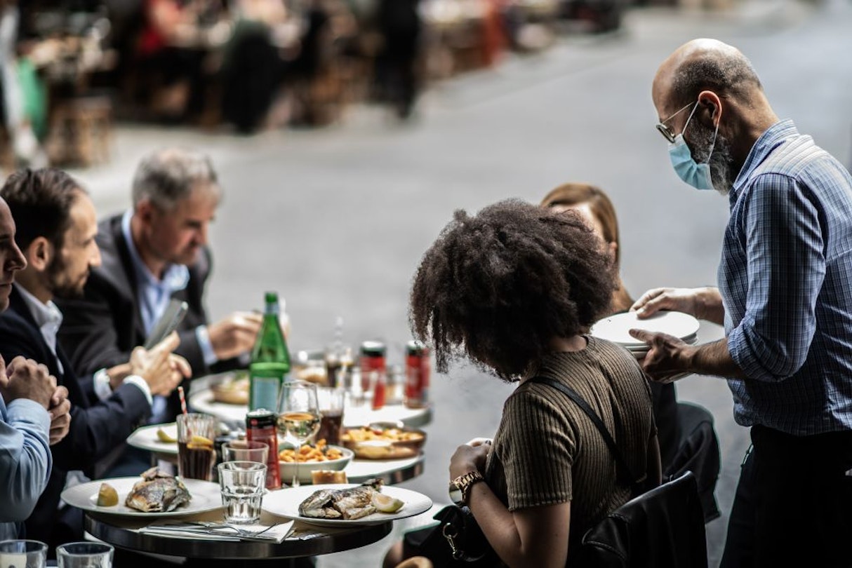 A waiter serves customers at a terrace of a restaurant in Paris, on June 15, 2020, as cafes and restaurants are allowed to serve customers inside, as well as on terraces, as part of the easing of lockdown measures taken to curb the spread of the COVID-19 pandemic, caused by the novel coronavirus. (Photo by Martin BUREAU / AFP) (Photo by MARTIN BUREAU/AFP via Getty Images)