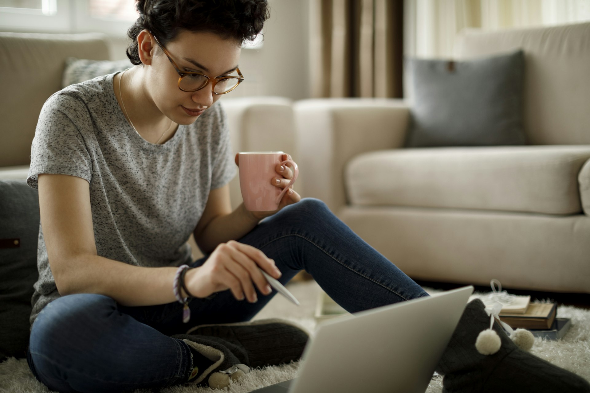 Young woman using laptop and drinking coffee at home