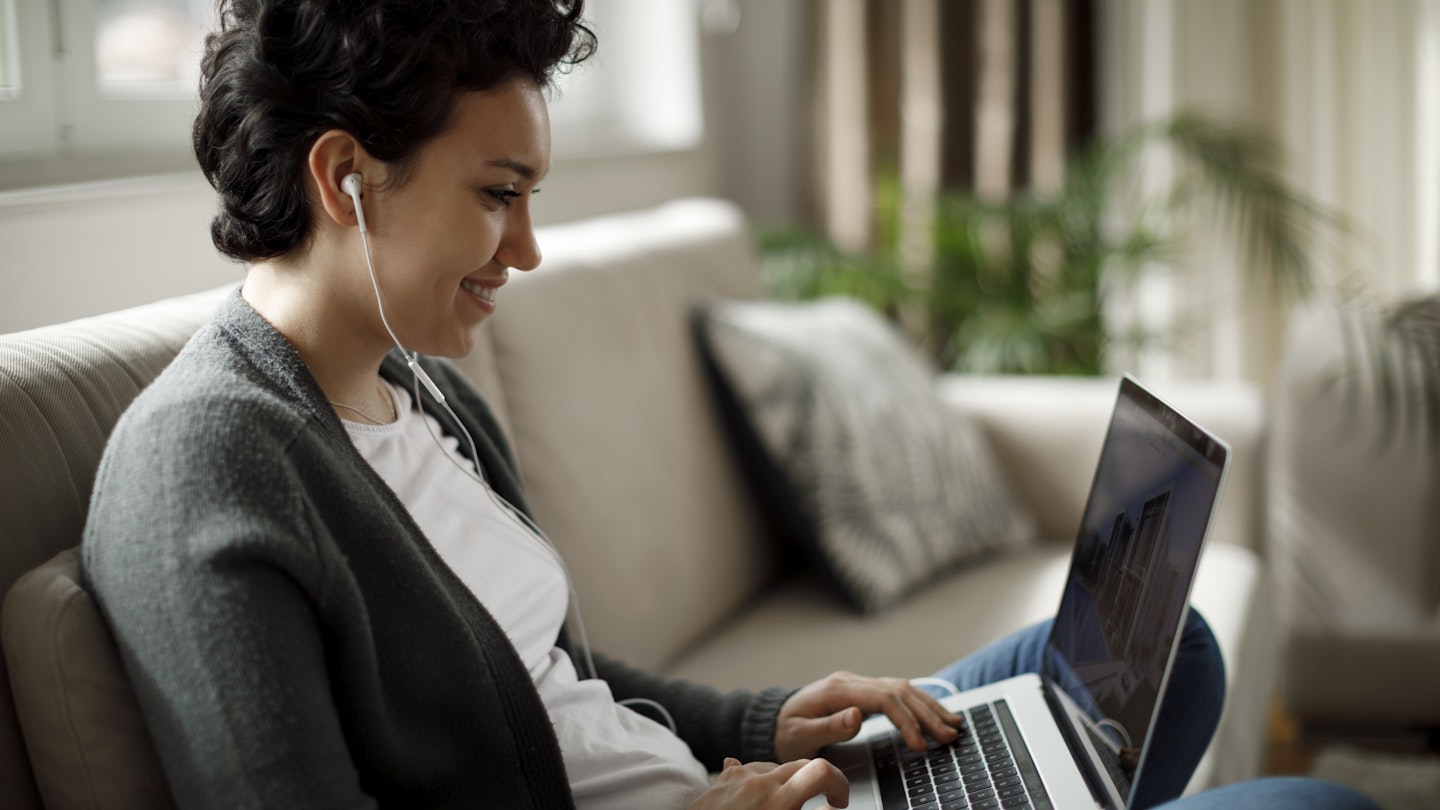 Young woman enjoying good music while working on laptop