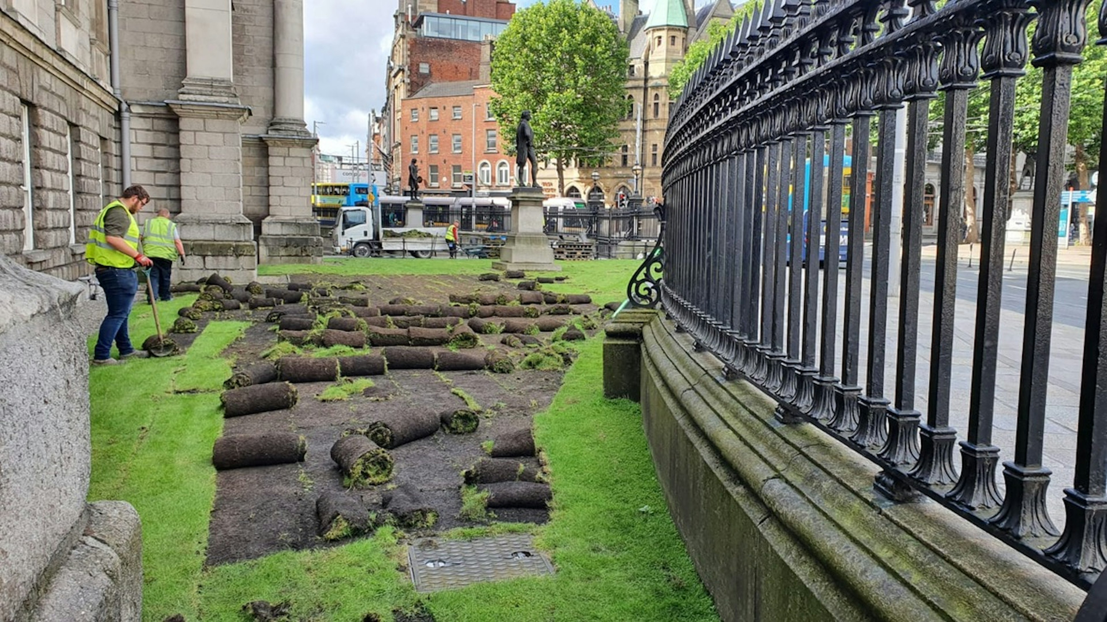 Gardeners digging up the front lawn of Trinity College