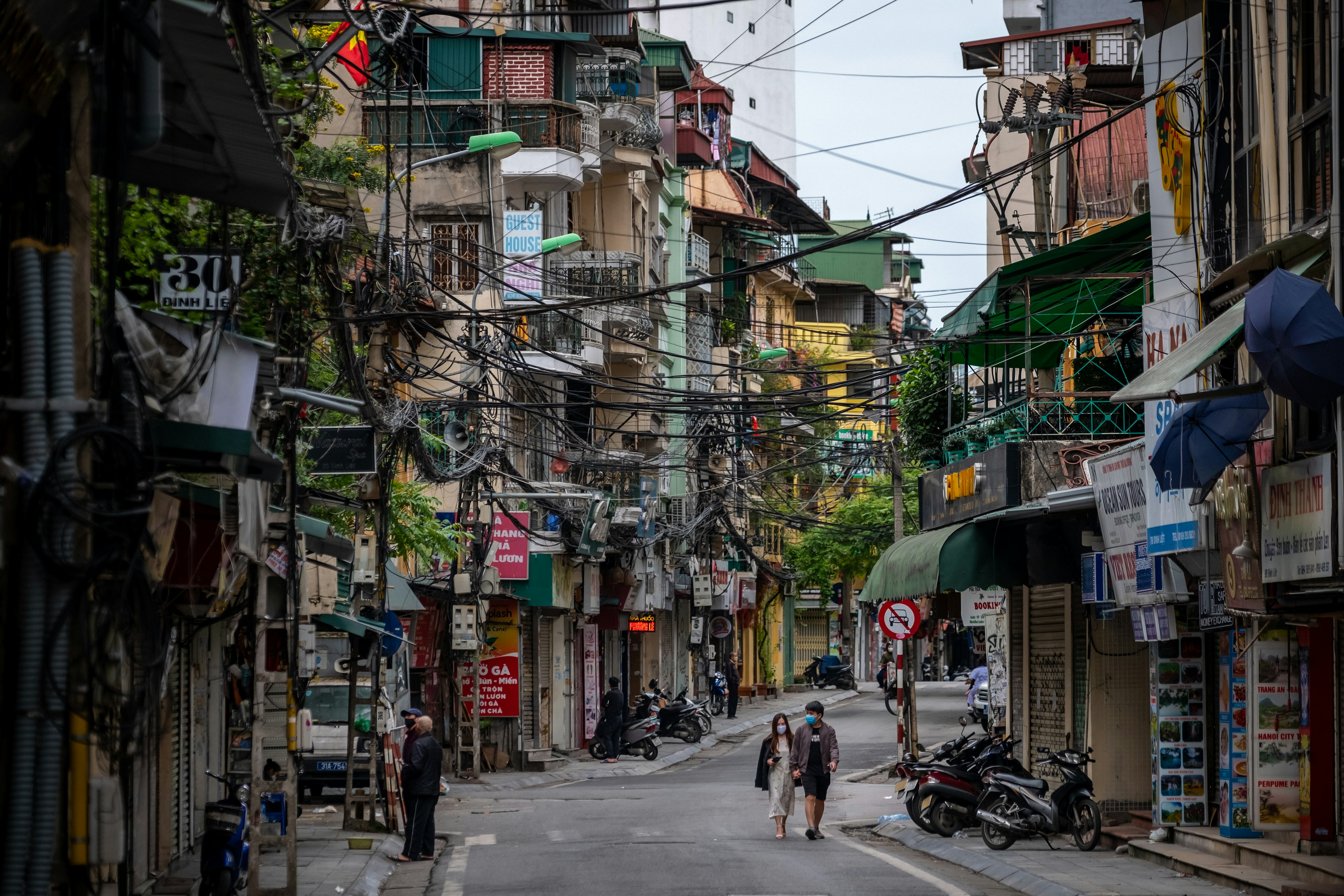 A couple walk down an empty, colorful, winding street in Hanoi, Vietnam