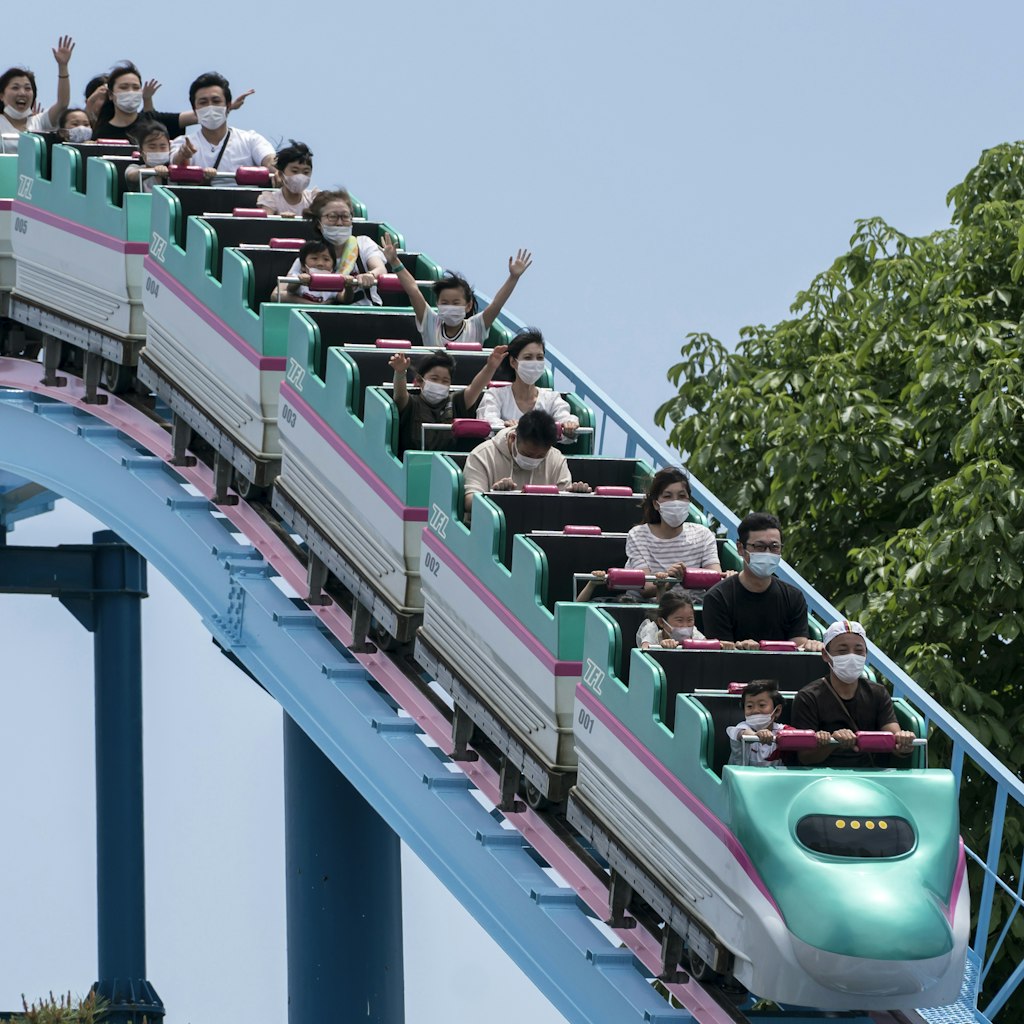 UTSUNOMIYA, JAPAN - MAY 17: Visitors wearing face masks ride a roller coaster at the Tochinoki Family Land amusement park on May 17, 2020 in Utsunomiya, Tochigi, Japan. Japan's Prime Minister Shinzo Abe announced on May 14 that the nationwide state of emergency has been lifted for 39 of the country's 47 prefectures after the number of new Covid-19 coronavirus cases decreased. However, Hokkaido, Tokyo, Kanagawa, Saitama, Chiba, Osaka, Kyoto and Hyogo will remain under the order until May 31.  (Photo by Tomohiro Ohsumi/Getty Images)