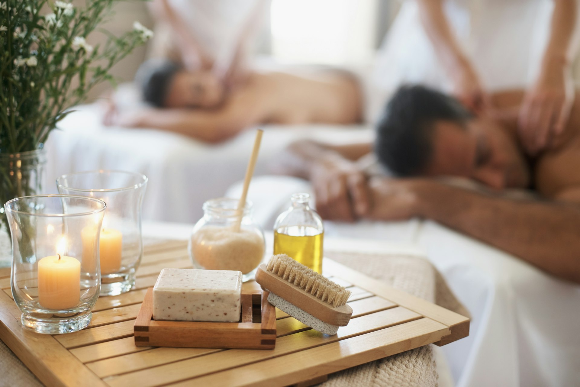A man and woman enjoy a luxurious massage in a white-walled spa.