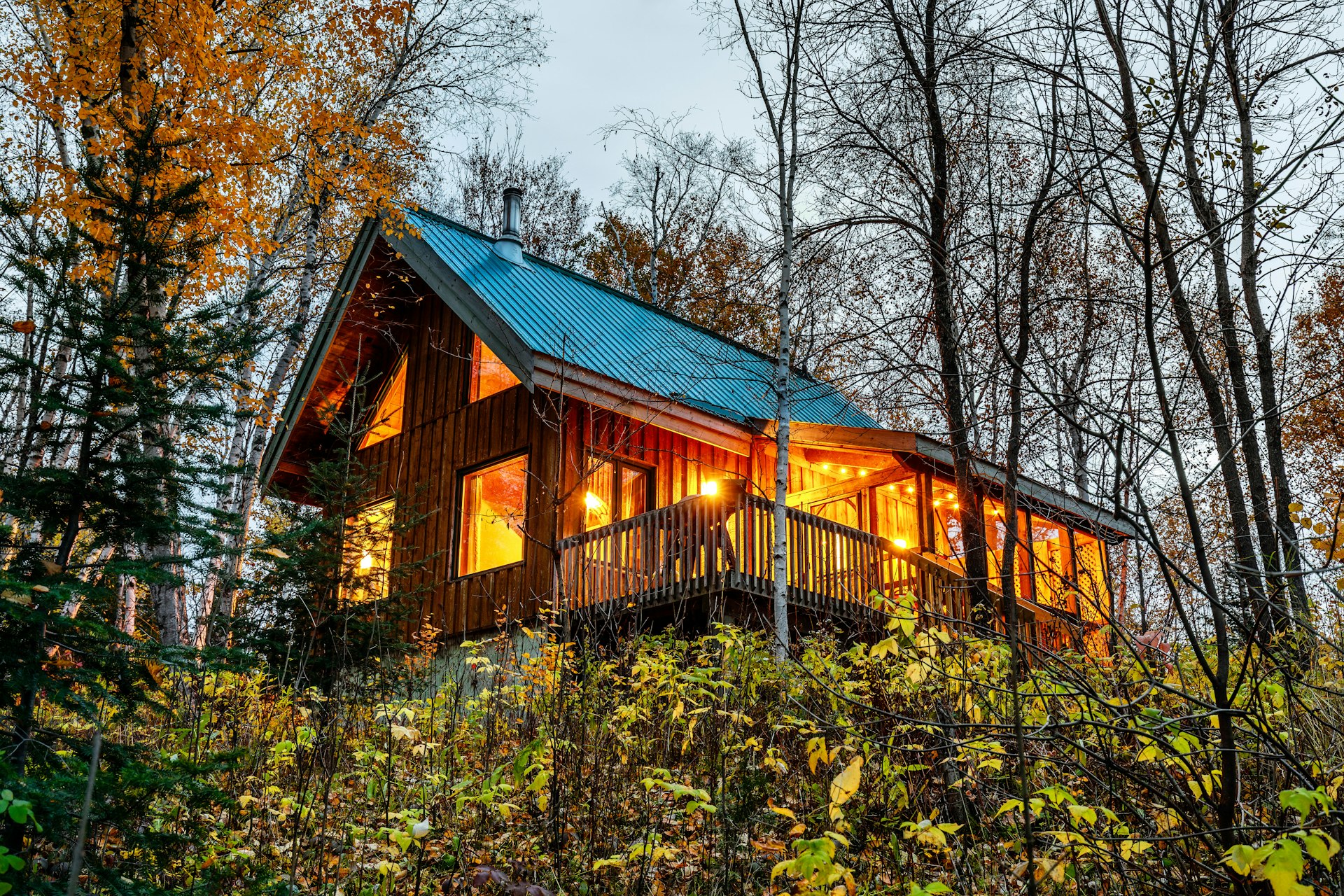 Wooden cabin in the woods, warm lights turned on inside.