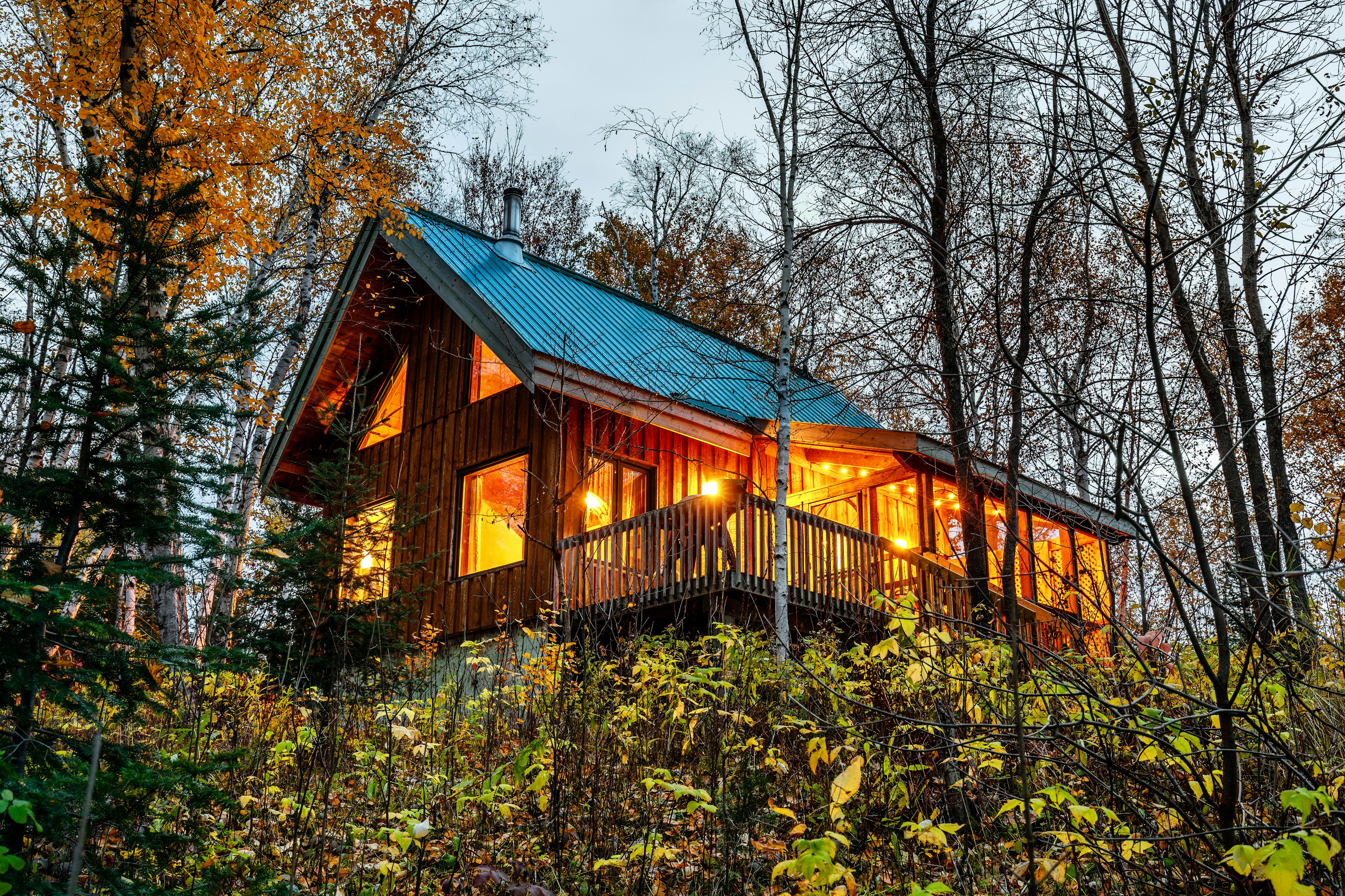 Wooden cabin in the woods, warm lights turned on inside.