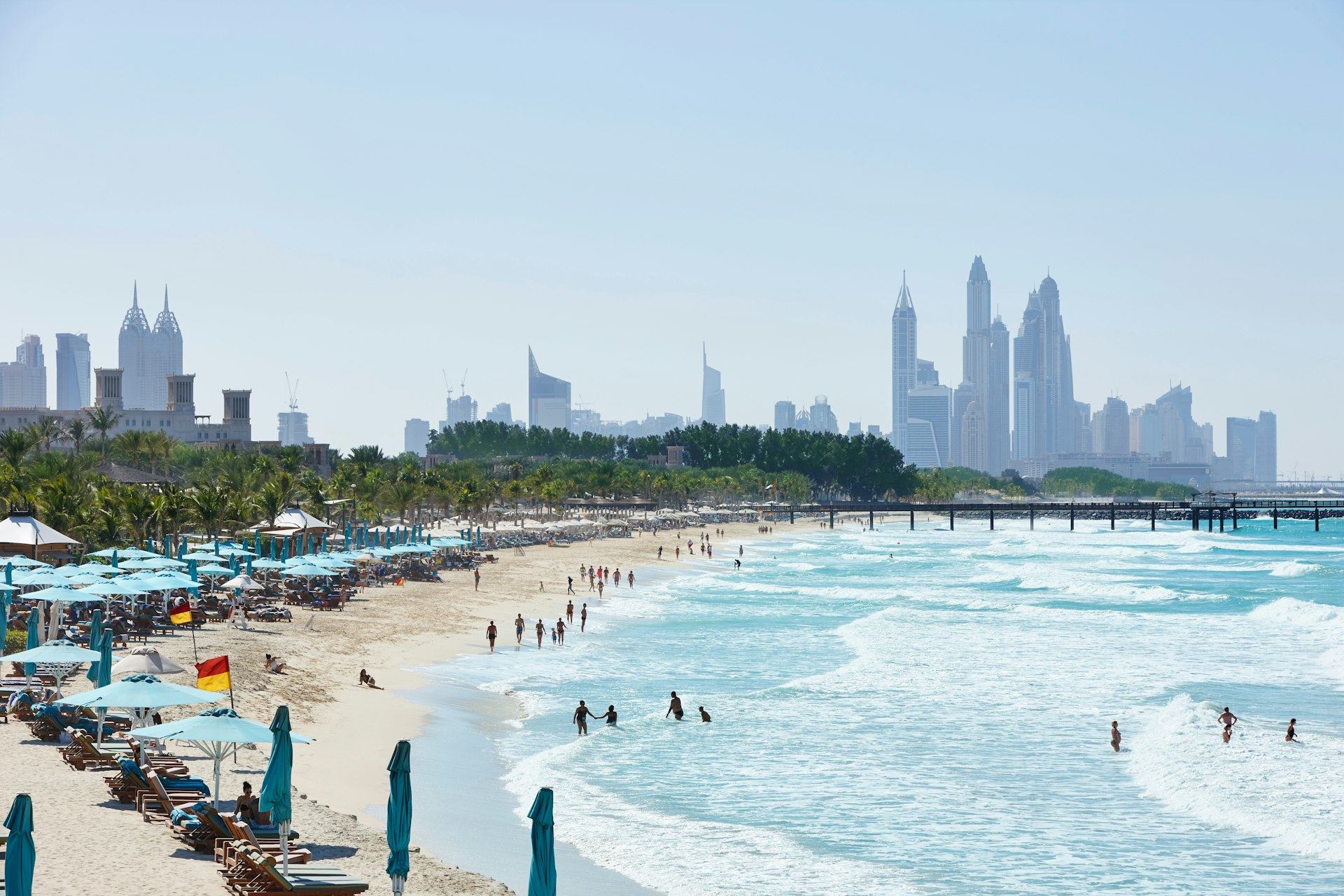 People in the water at Jumeirah Beach with the Dubai skyline in the distance