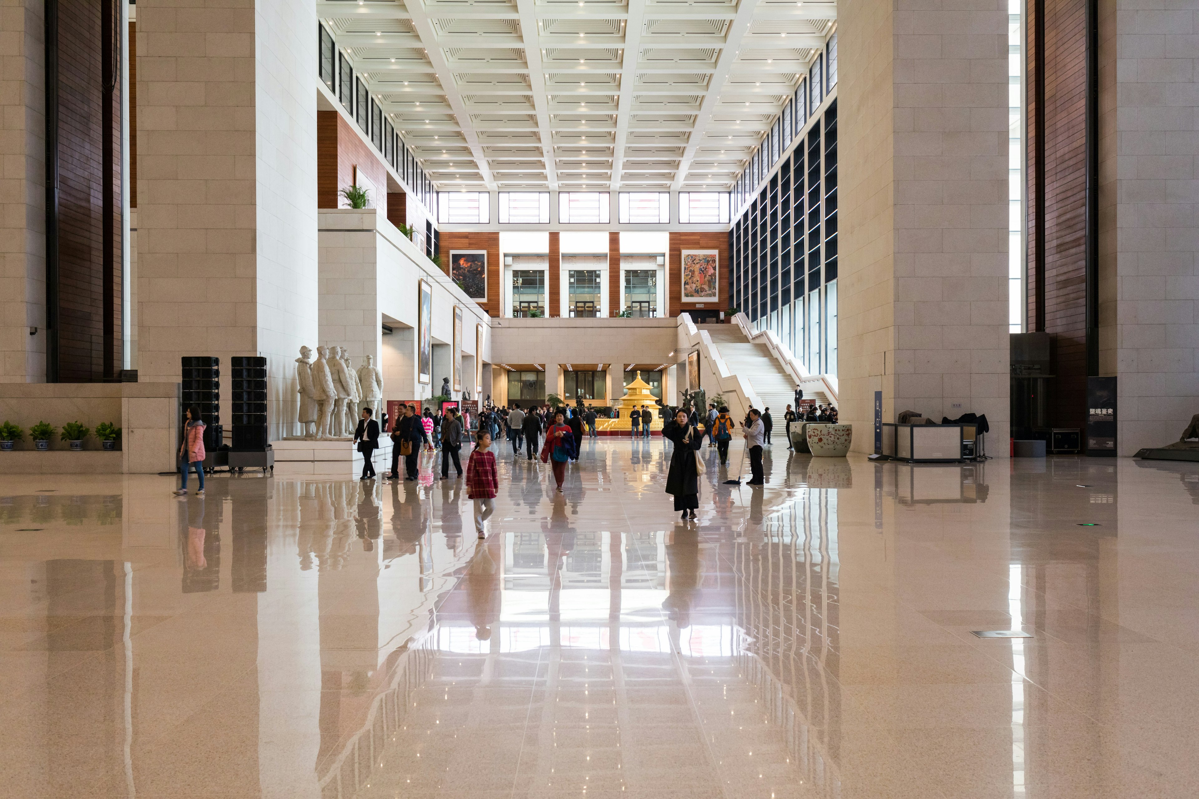 A wide open indoor exhibition space with tourists moving around