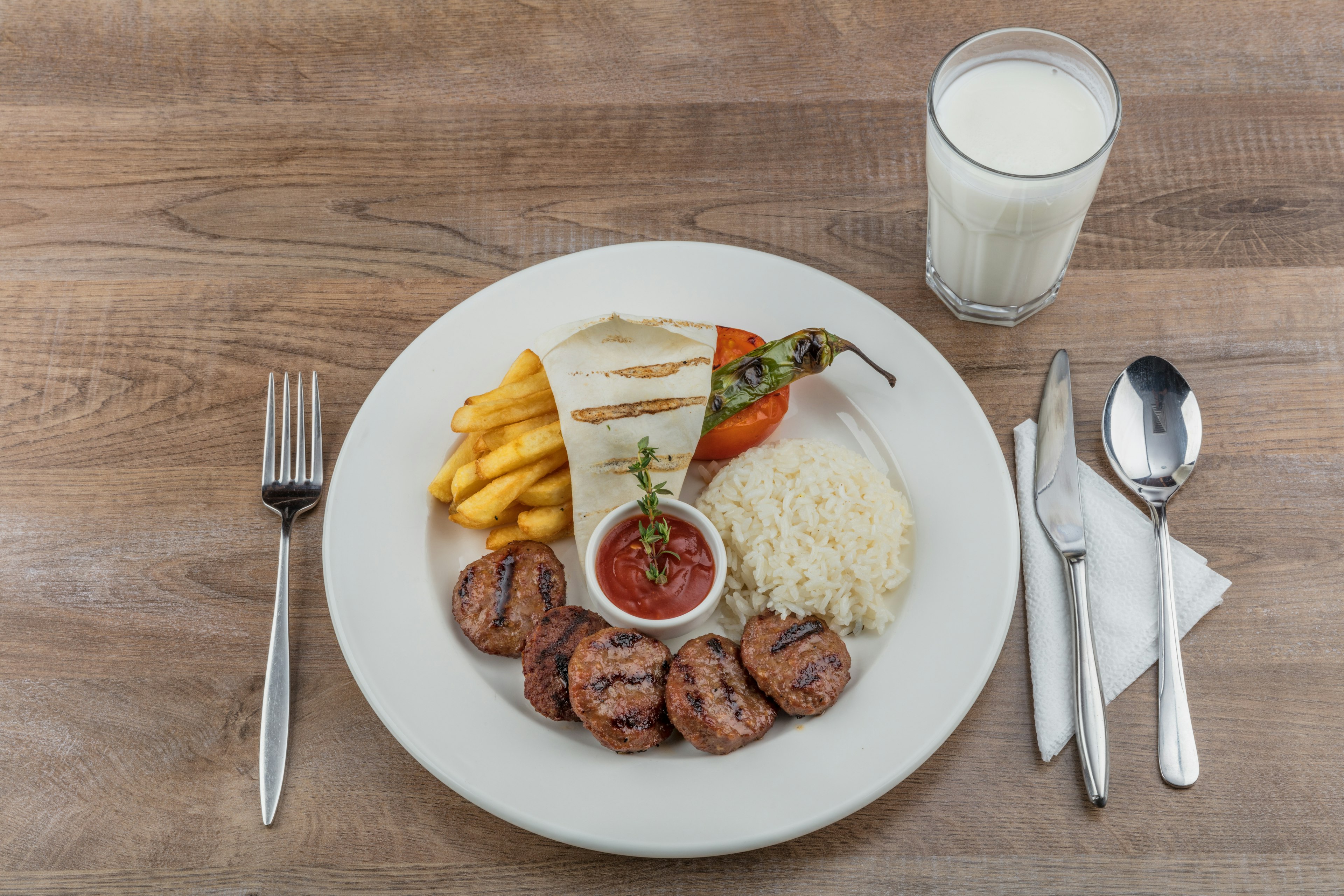 Turkish meatballs with fresh green peppers and pickles on a wooden table