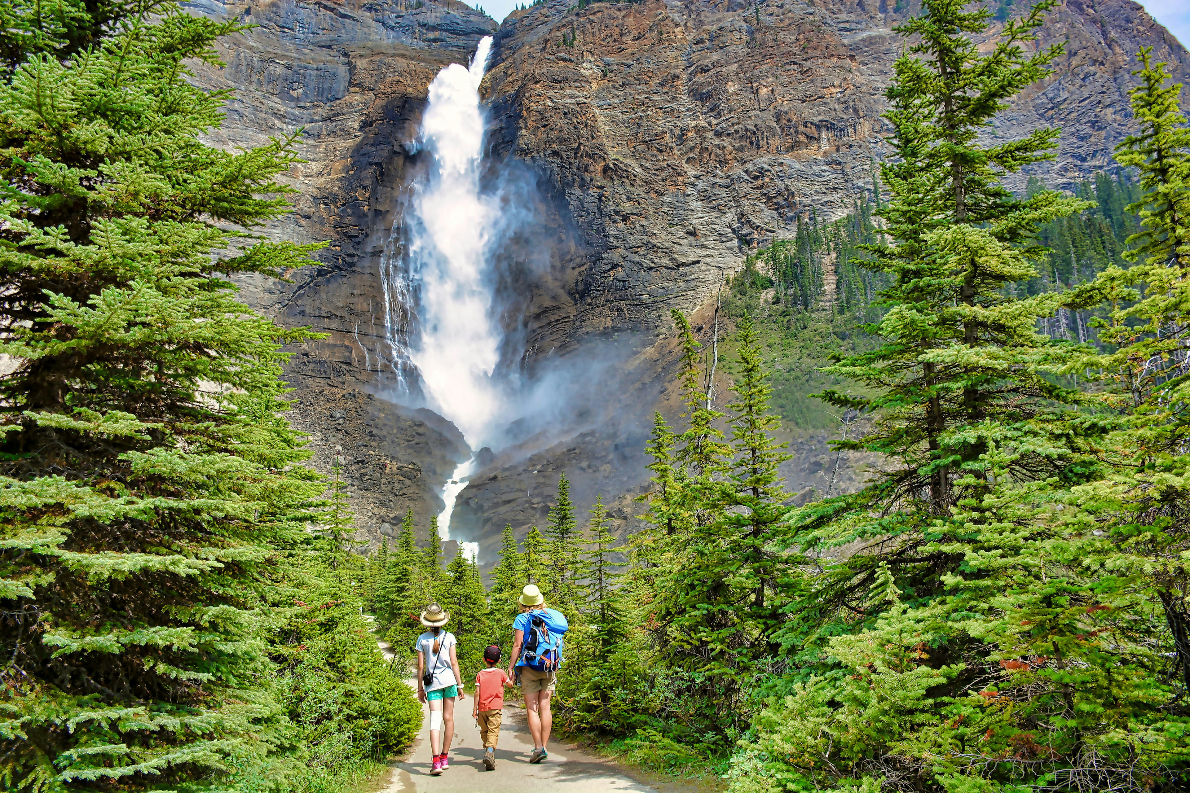 Mother and her two children walk toward Takakkaw Falls in Yoho National Park