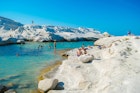 August, 2018: Swimmers and sunbathers at Sarakiniko beach with white volcanic rocks.