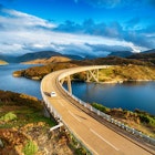 The Kylesku Bridge spanning Loch a' Chàirn Bhàin in the Scottish Highlands, which is a landmark on the North Coast 500 tourist driving route.
