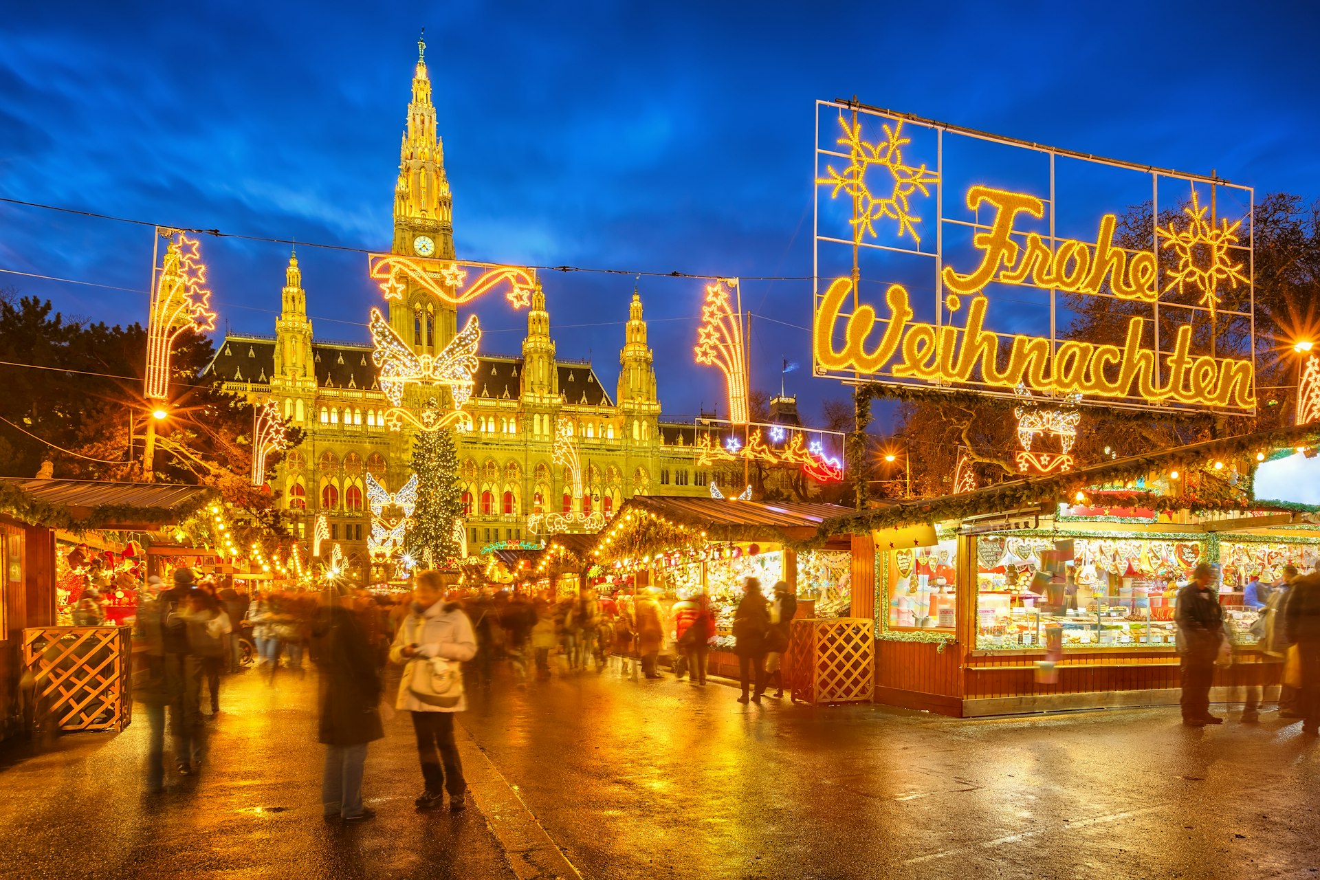 An evening view of the Christmas market in Vienna, with fairy lights illuminating the various market stalls.