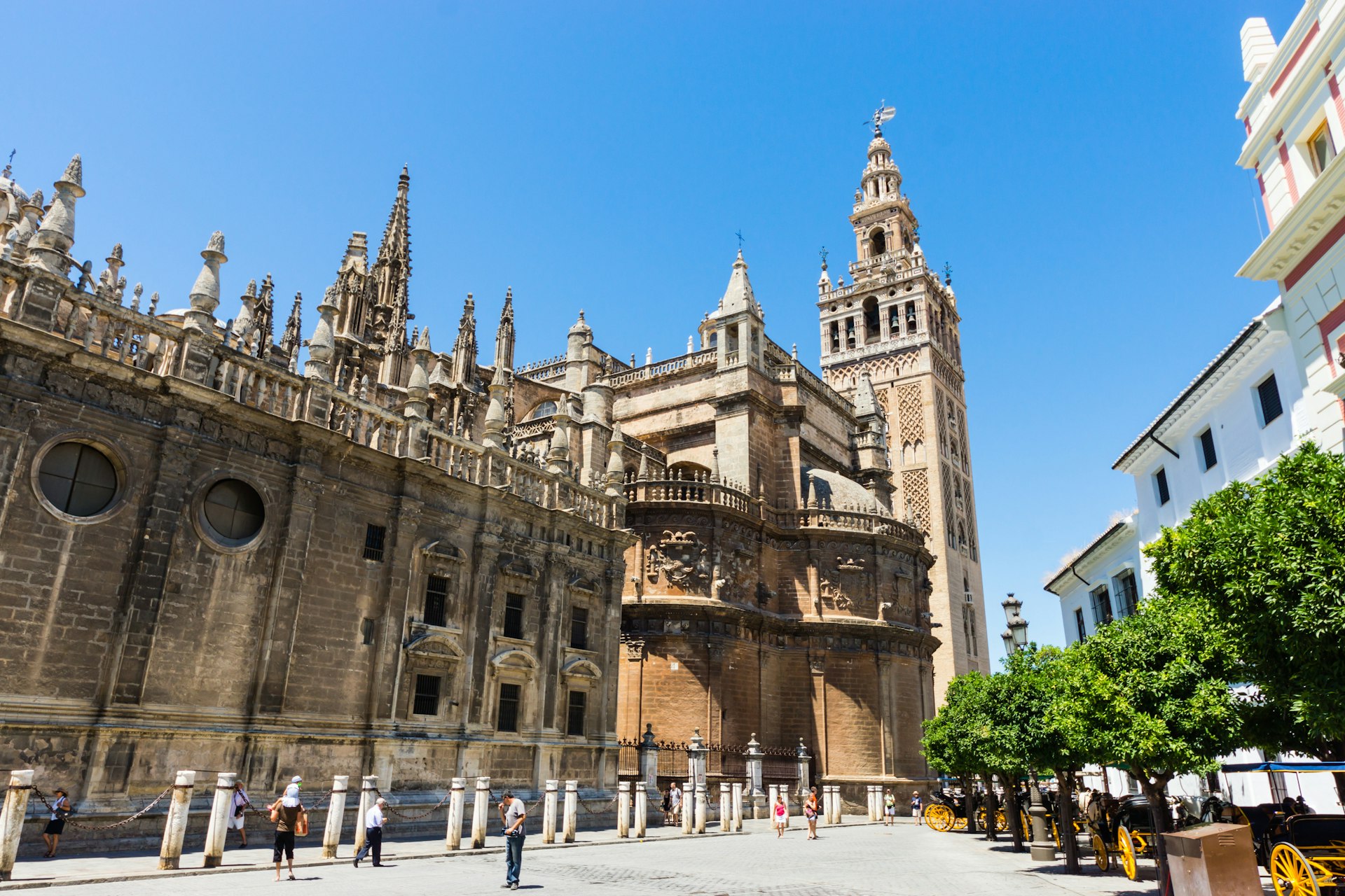 The huge Gothic exterior of Seville's Cathedral; at one end is its Giralda bell tower, resembling a minaret with a delicate brick-pattern decoration.