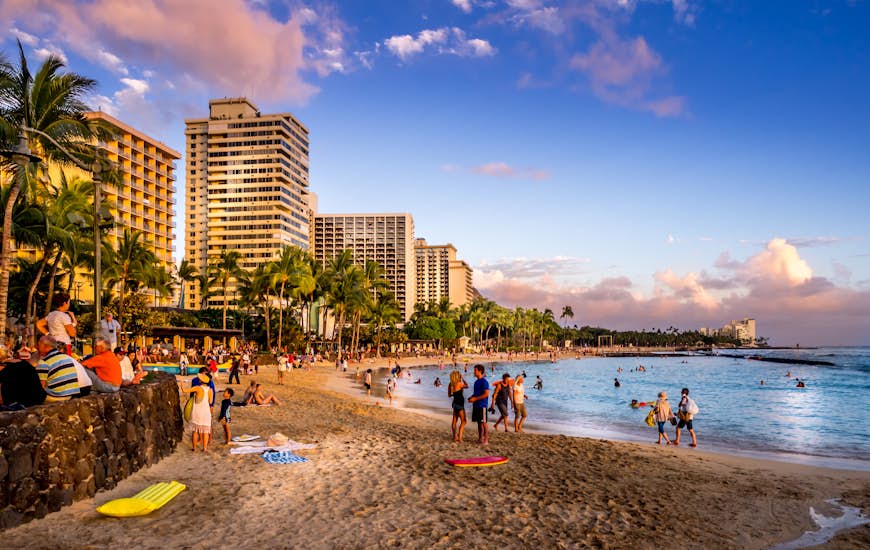 Tourists on the beach front at sunset on Waikiki beach in Oahu 