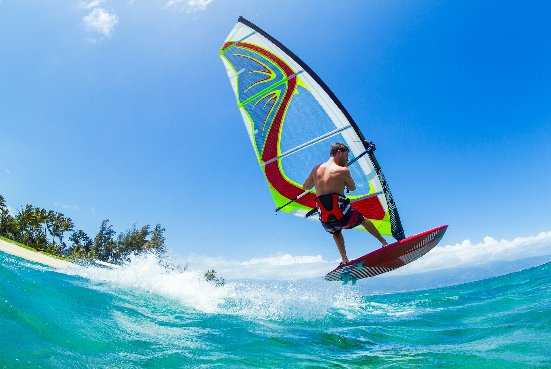 a man on a windsurfing board skips over a wave