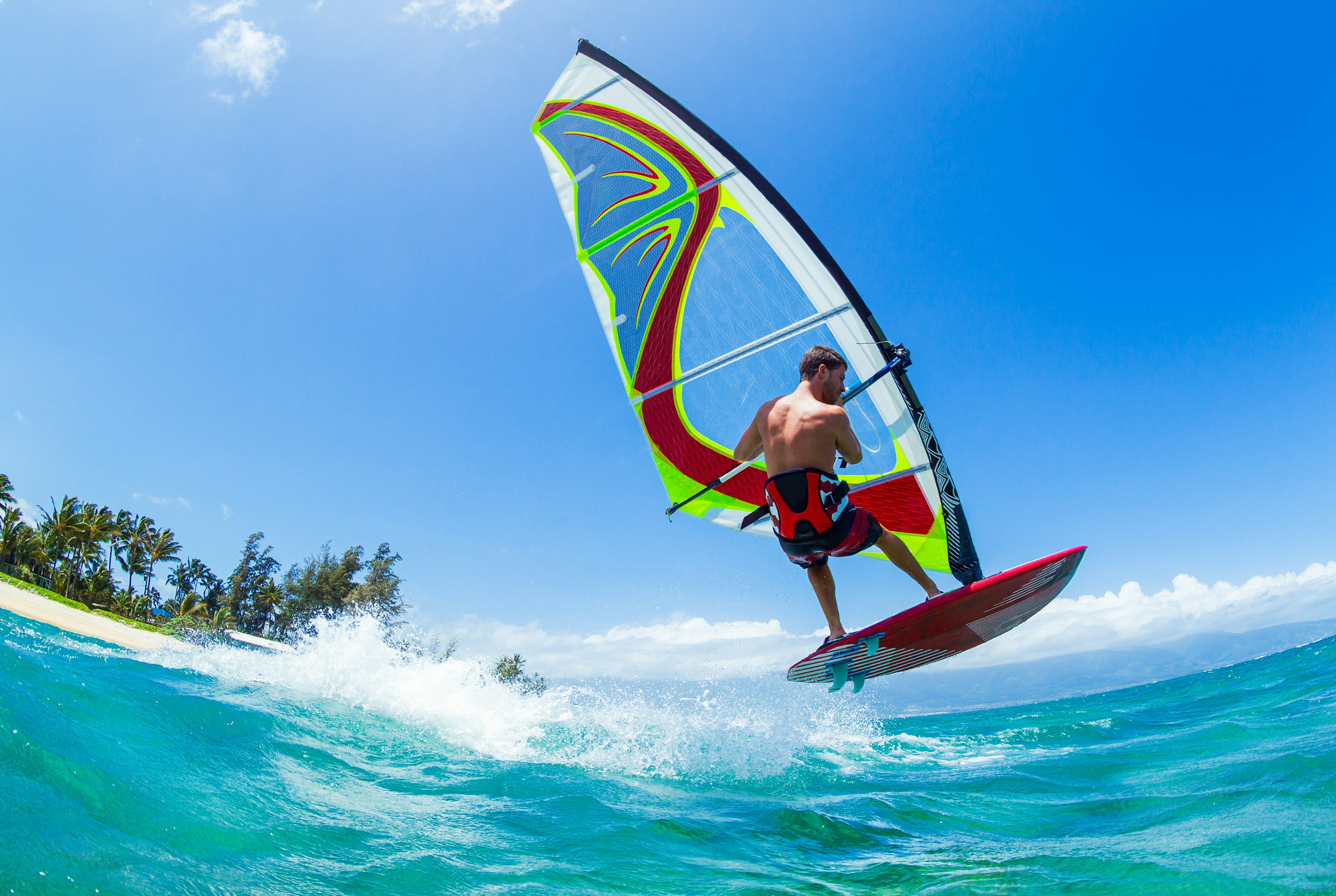 a man on a windsurfing board skips over a wave