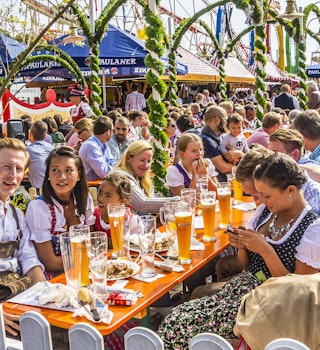 People dressed in traditional costumes are sitting in the beergarden.