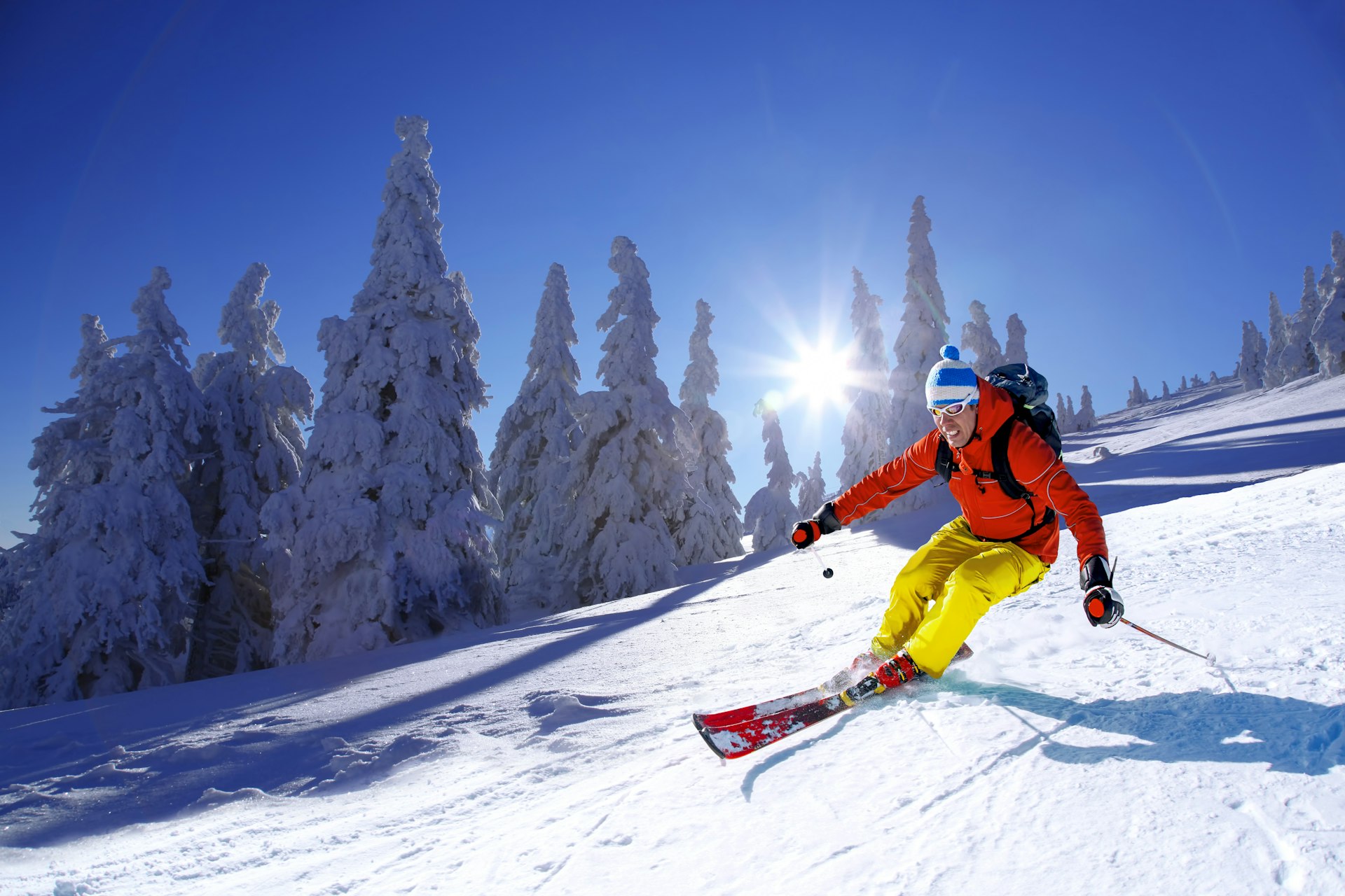 A skier skiing downhill in high mountains against sunshine