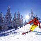 Skier skiing downhill in high mountains against sunshine.