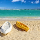 White and yellow kayaks on sandy Caribbean beach.