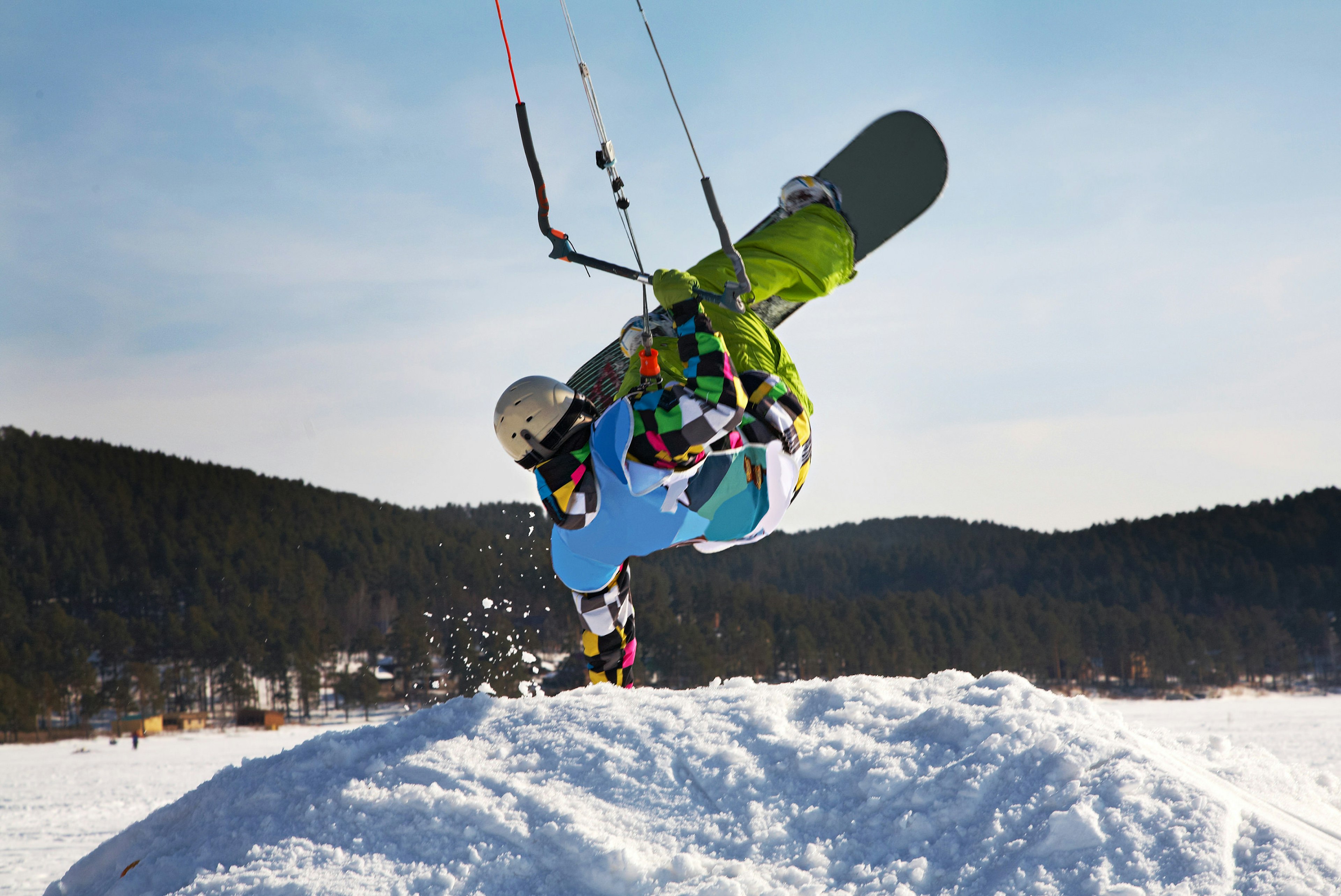 Man doing a handstand on a snowdrift while snowkiting on a frozen lake.