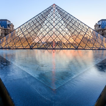 PARIS, FRANCE - JULY 19: The Louvre Pyramid at dusk during the Michelangelo Pistoletto Exhibition on July 19, 2014 in Paris. The Pyramid is the main entrance to the Louvre Museum.