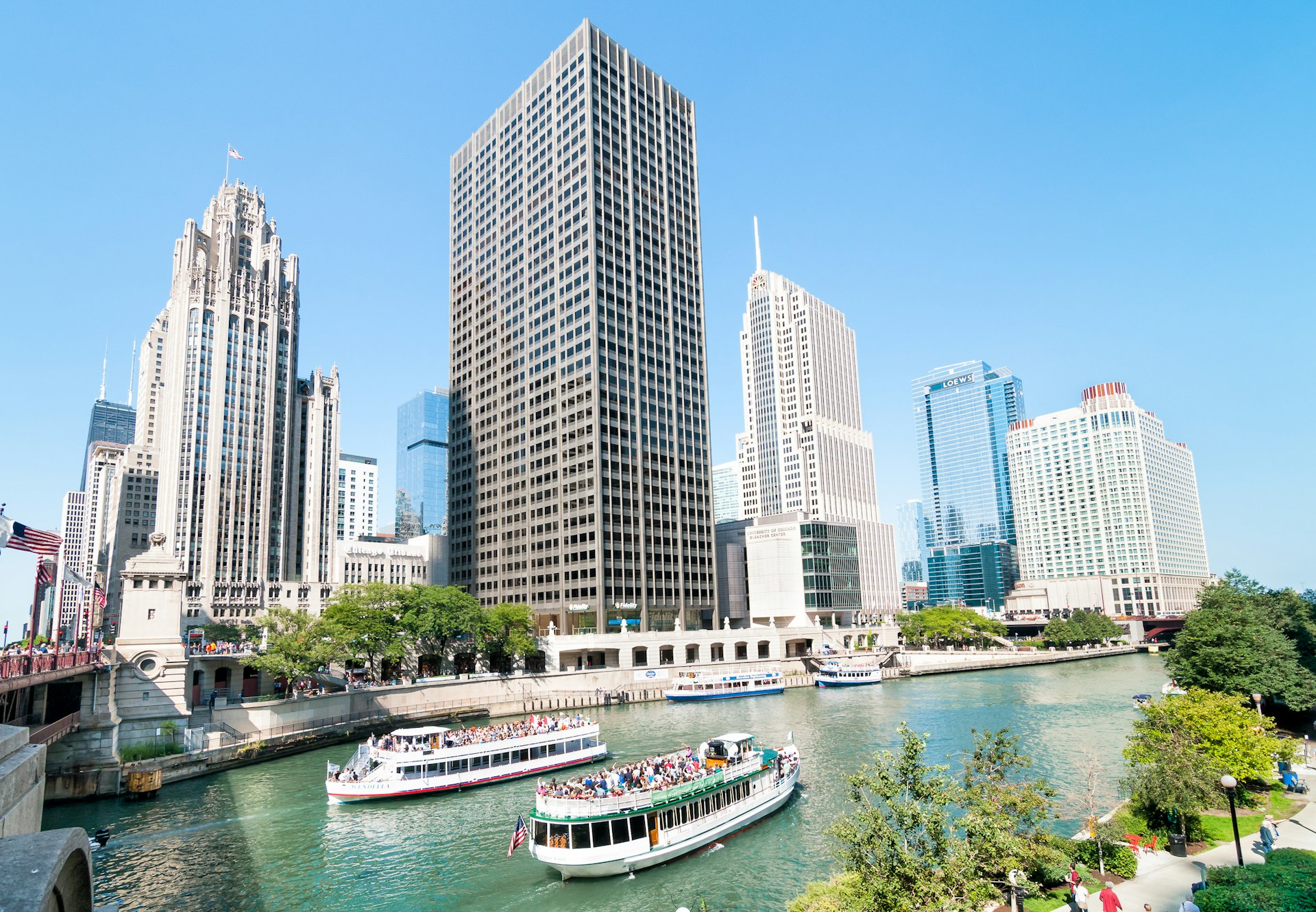 Ferries traveling on a river towards Lake Michigan before the Chicago skyline