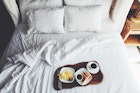 Breakfast on a tray in bed in hotel, white linen, wooden interior