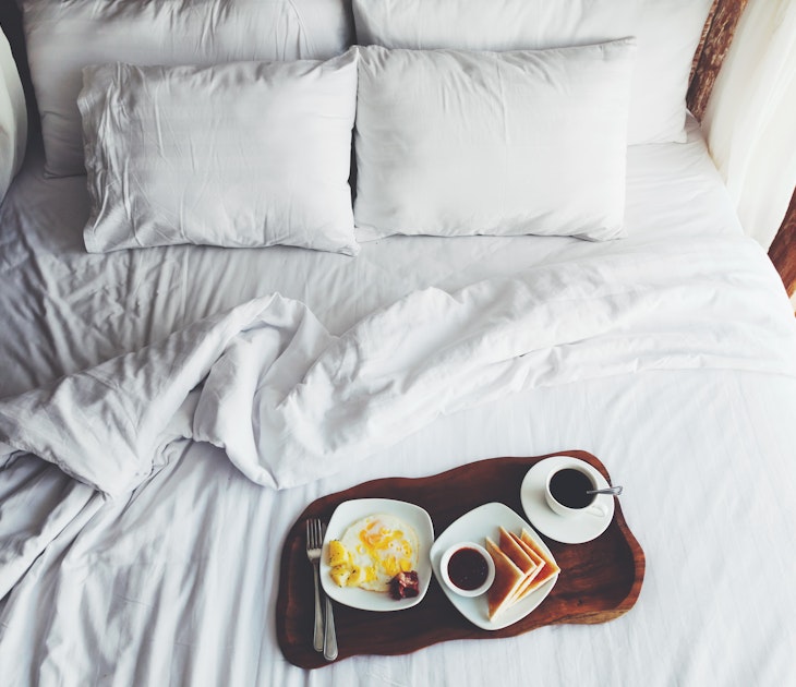 Breakfast on a tray in bed in hotel, white linen, wooden interior