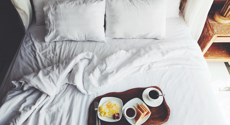 Breakfast on a tray in bed in hotel, white linen, wooden interior