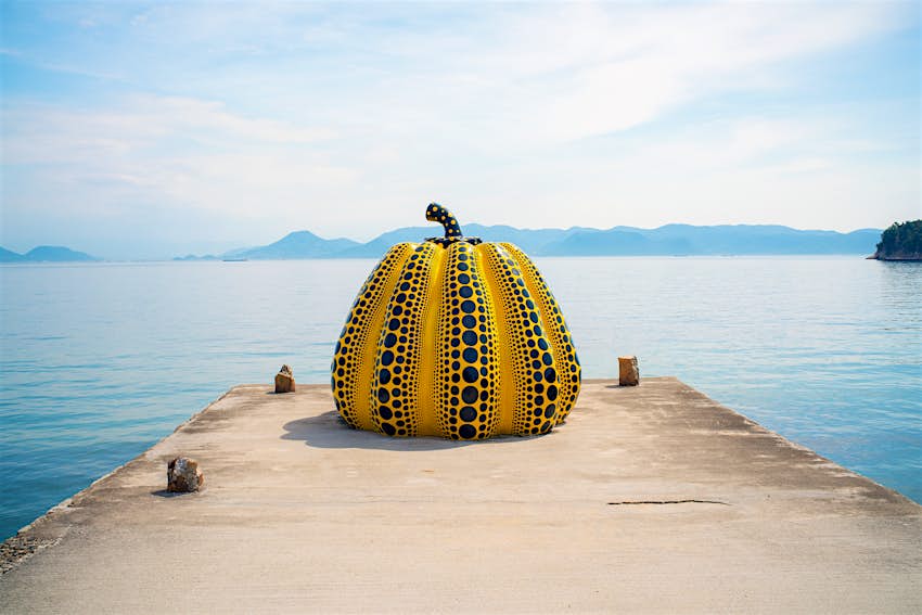 Yayoi Kusama's giant pumpkin sculpture in front of the sea. 
