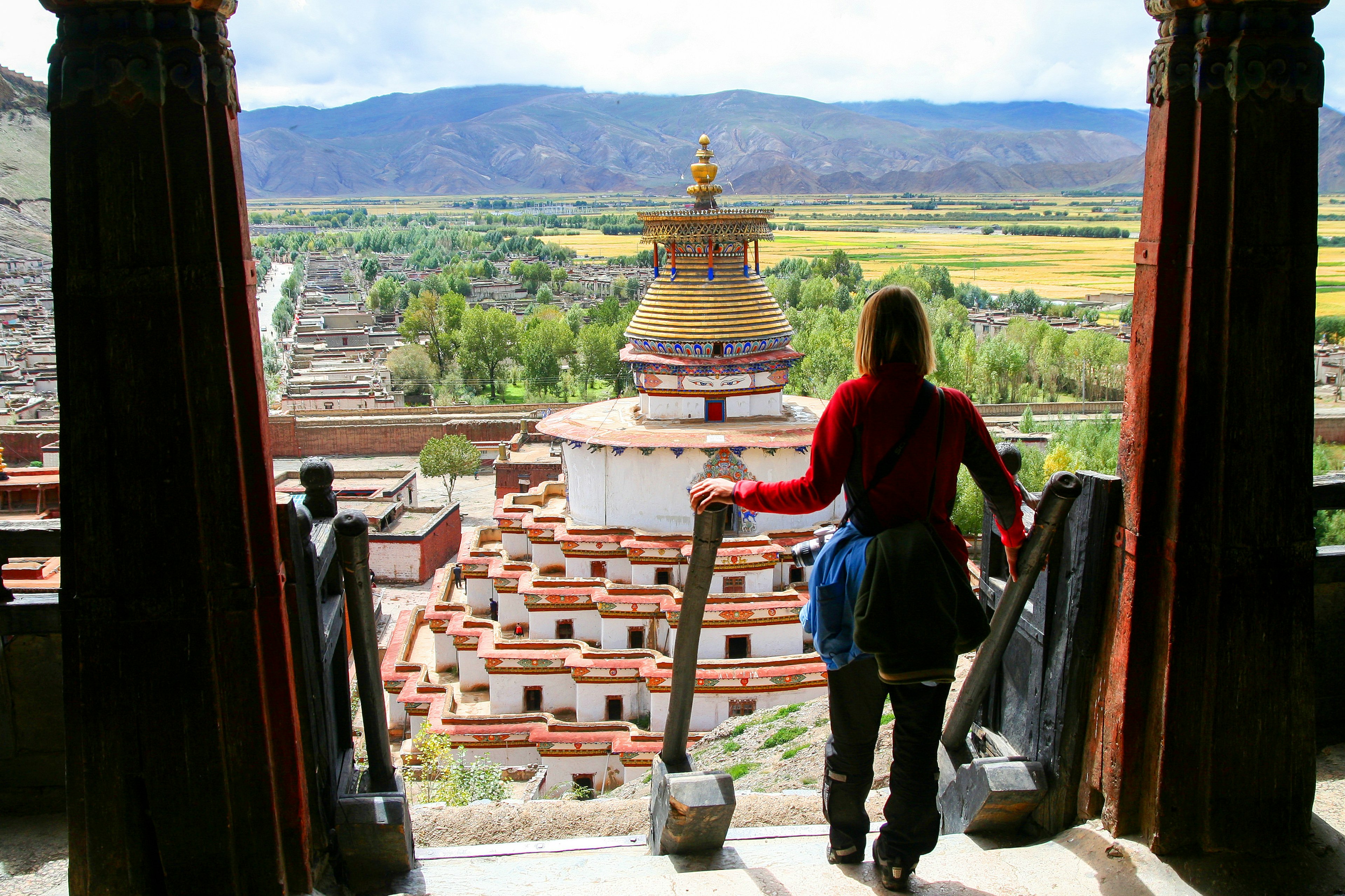 A woman visiting stupa is about to descend a staircase of a monastery