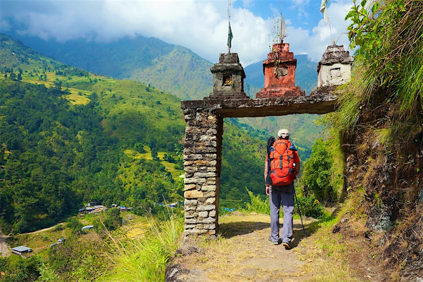 Male hiker enters a stone gate to a Nepalese village on the Annapurna Circuit Trek