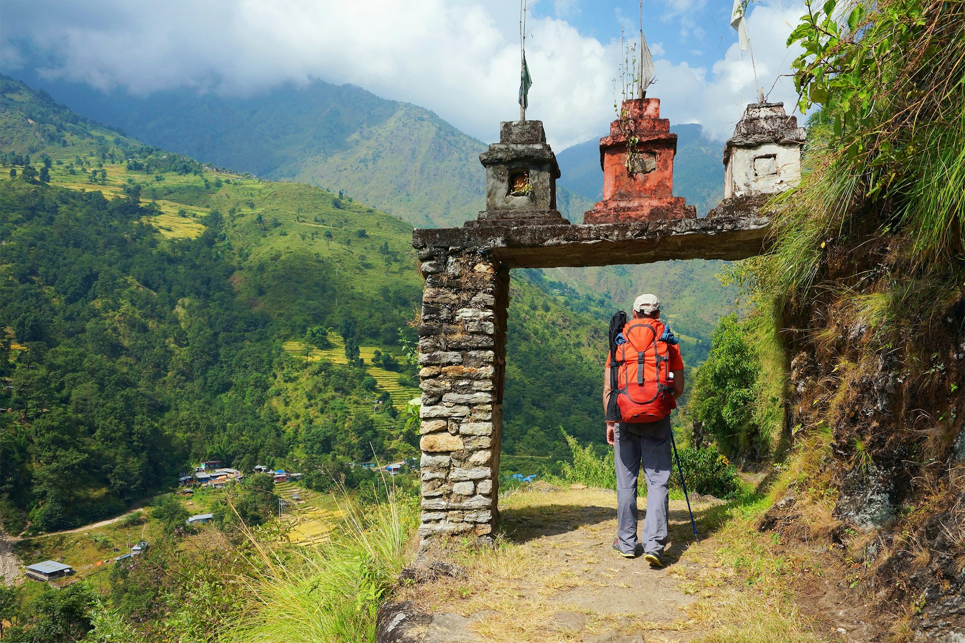 A hiker approaching an archway on a mountainous trail in Nepal