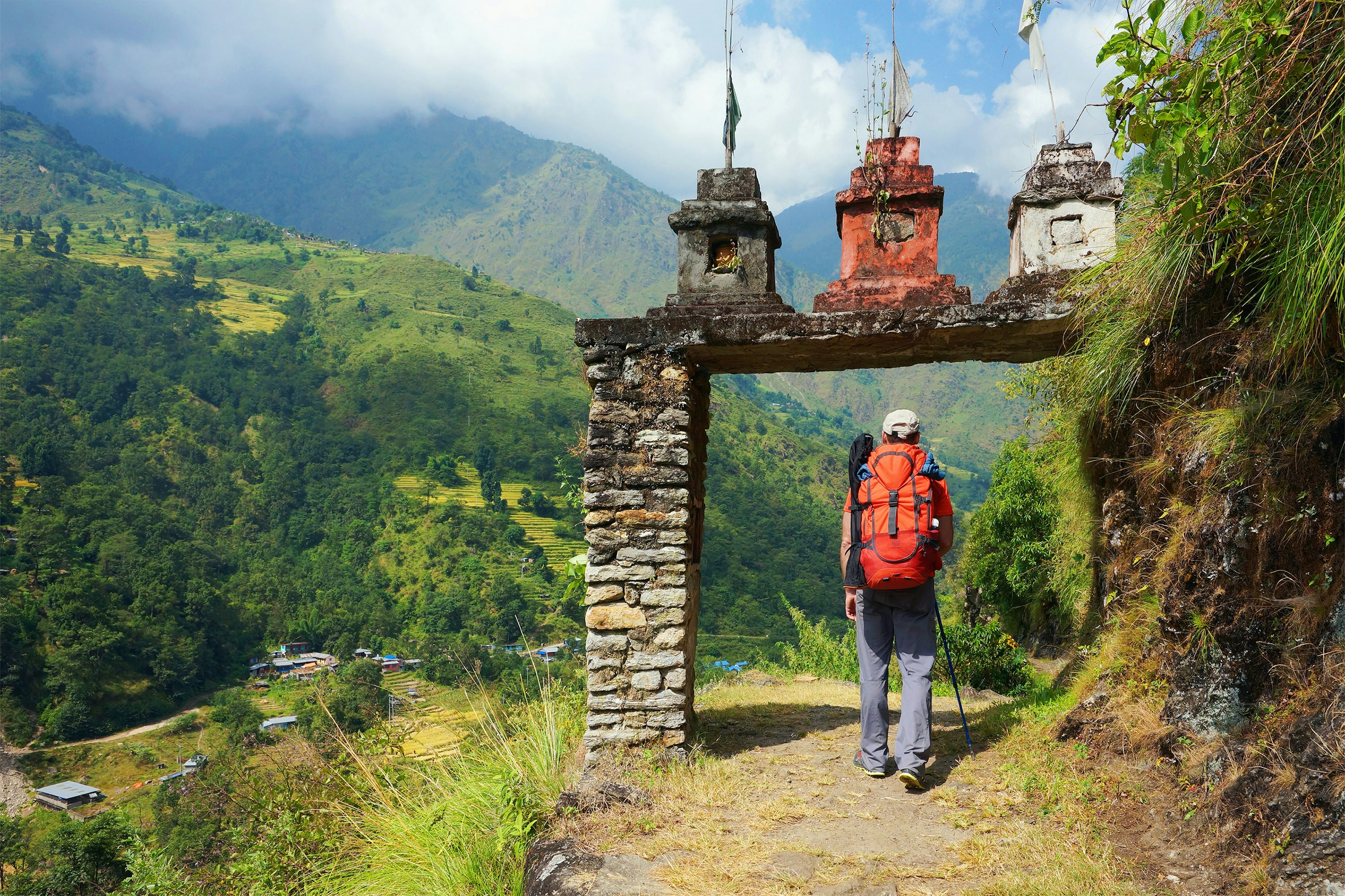 A hiker approaching an archway on a mountainous trail in Nepal