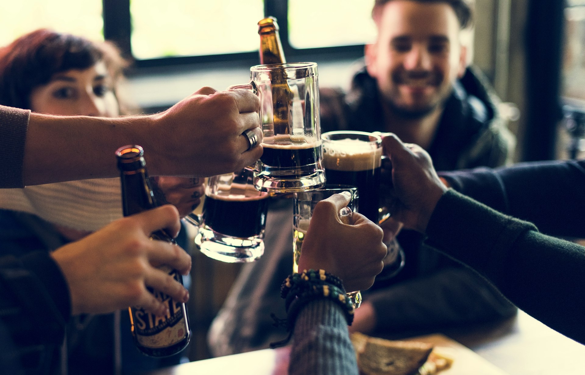 A group of friends in a bar clink their glasses together