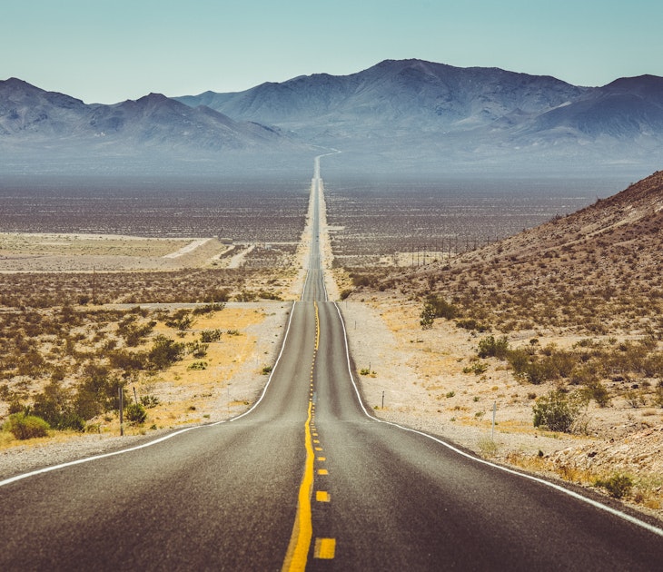 Long straight road through barren desert in the American Southwest with extreme heat haze on a sunny day.