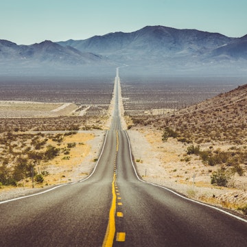Long straight road through barren desert in the American Southwest with extreme heat haze on a sunny day.
