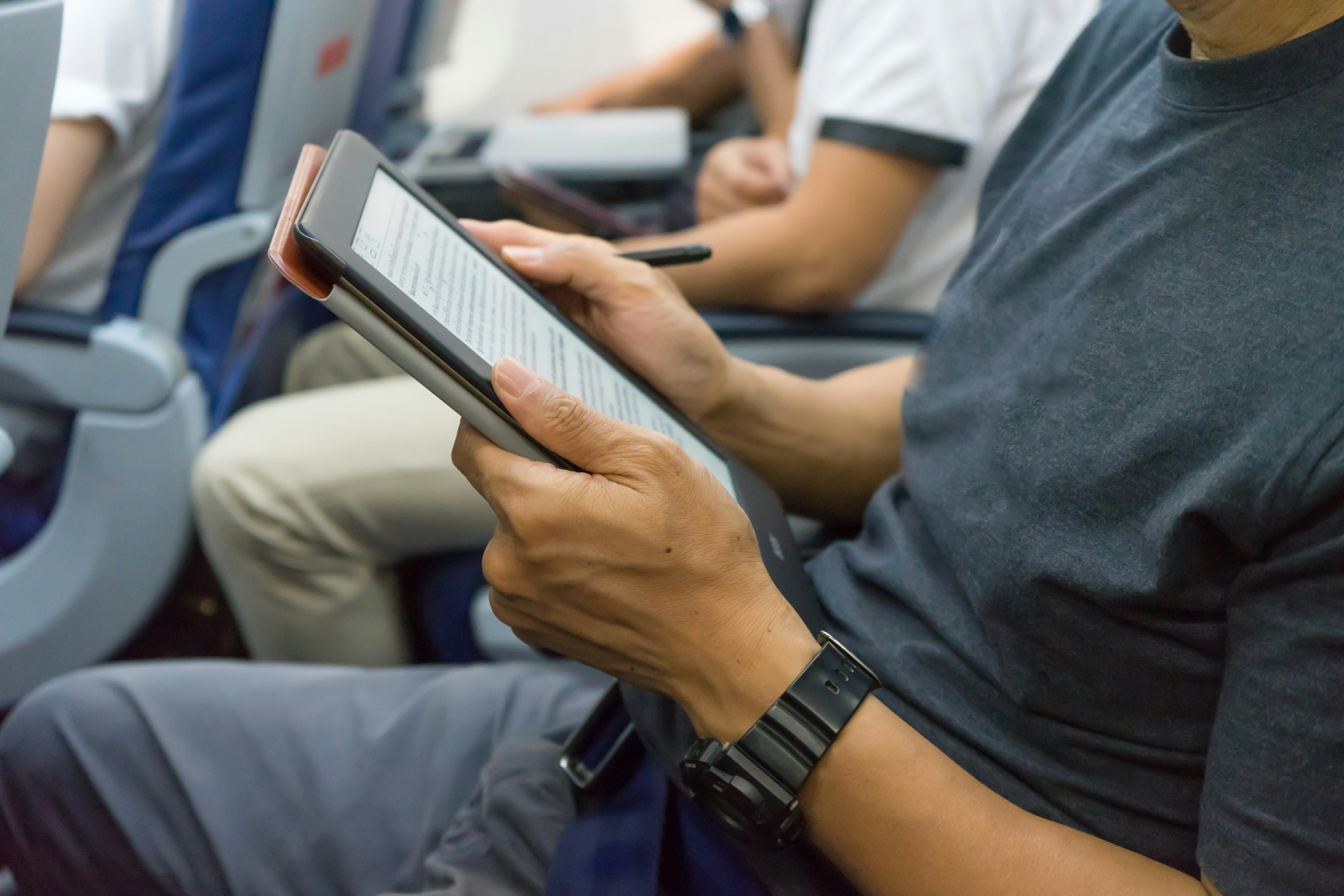 a man holds an e-reader on a plane.