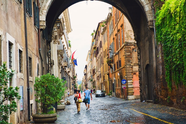 Tourists stroll along a cobbled street in Rome