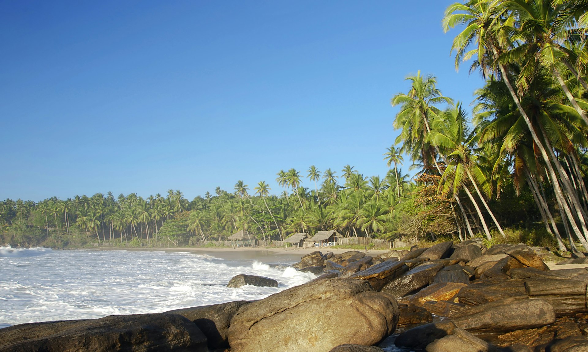 Beautiful tropical beach with boulders and palm trees lit by a morning sun in Tangalla, Sri Lanka.