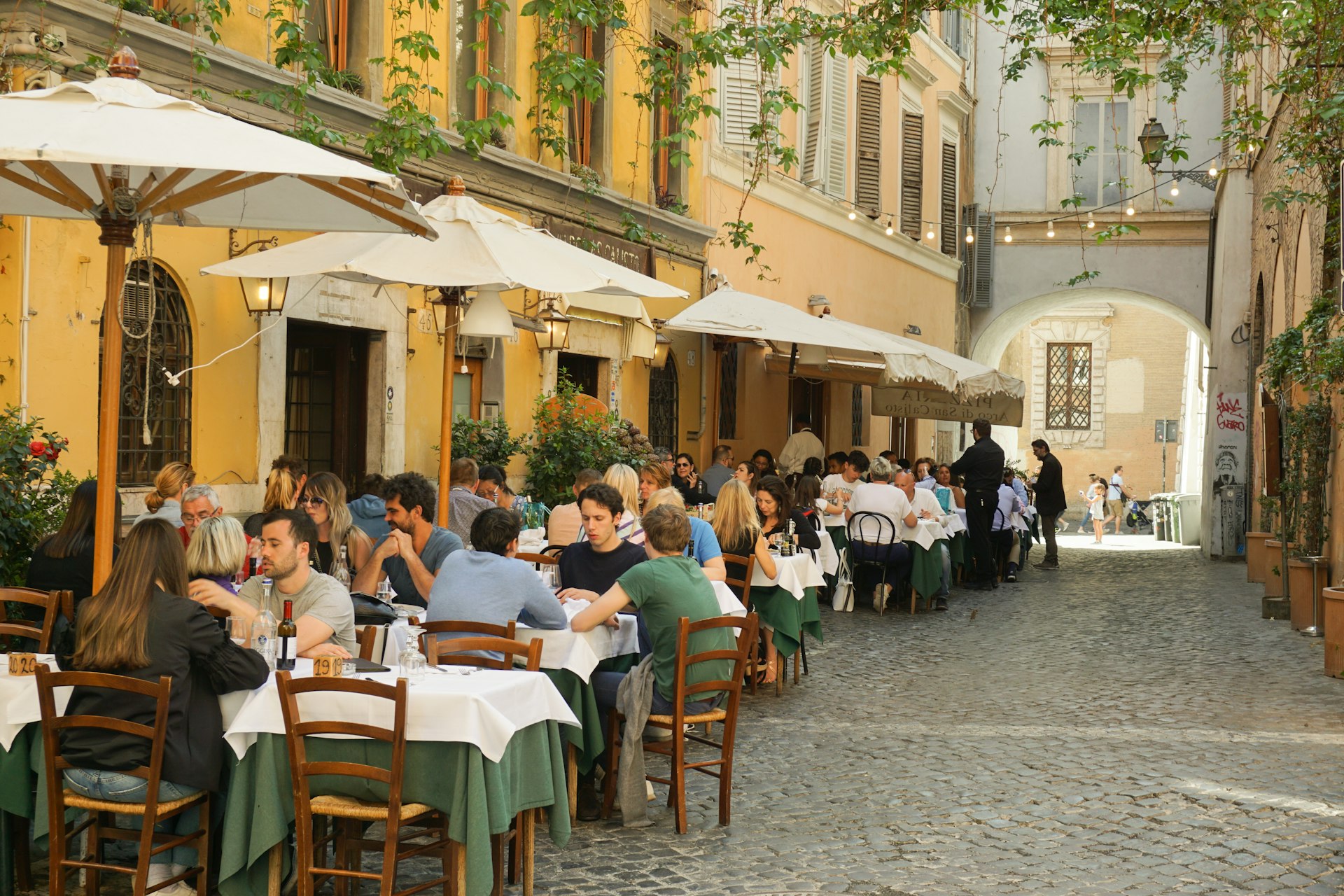 A series of outside tables full of diners lining a cobbled street 