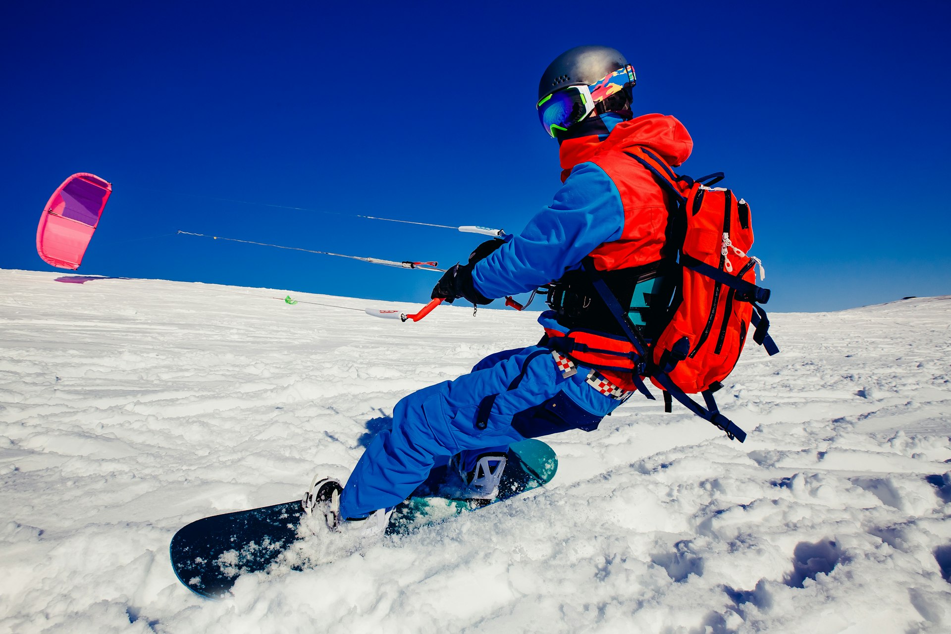 A snowboarder with a kite on fresh snow during winter