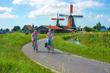 July 16, 2017: Cyclists pass through the Zaanse Schans windmill area in Amsterdam. 