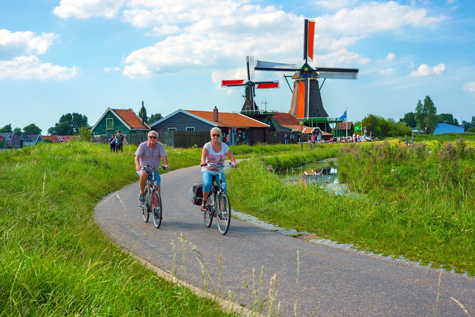 July 16, 2017: Cyclists pass through the Zaanse Schans windmill area in Amsterdam. 
