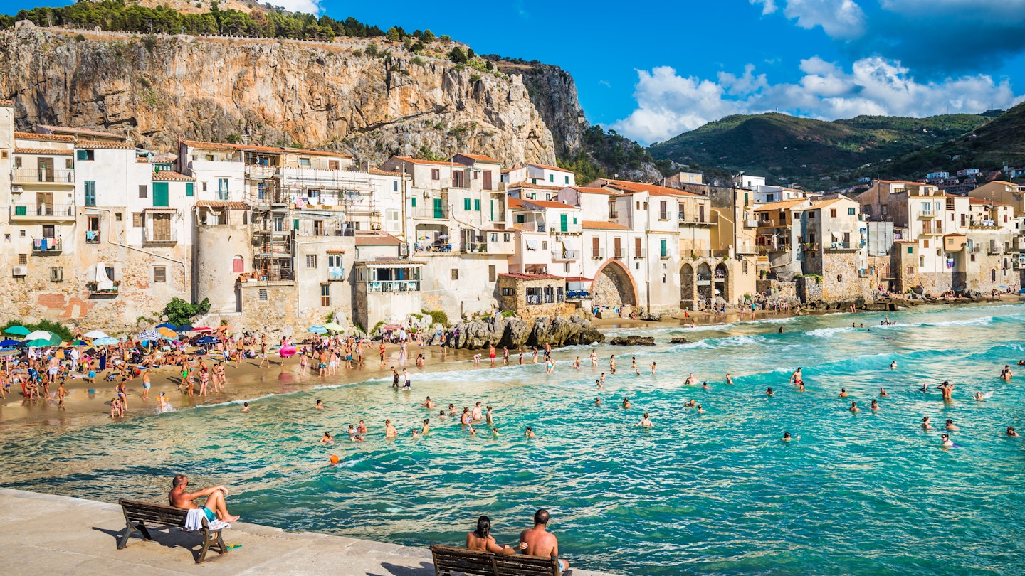 AUGUST 12, 2017: Visitors crowd the beach at Cefalu on a sunny day.