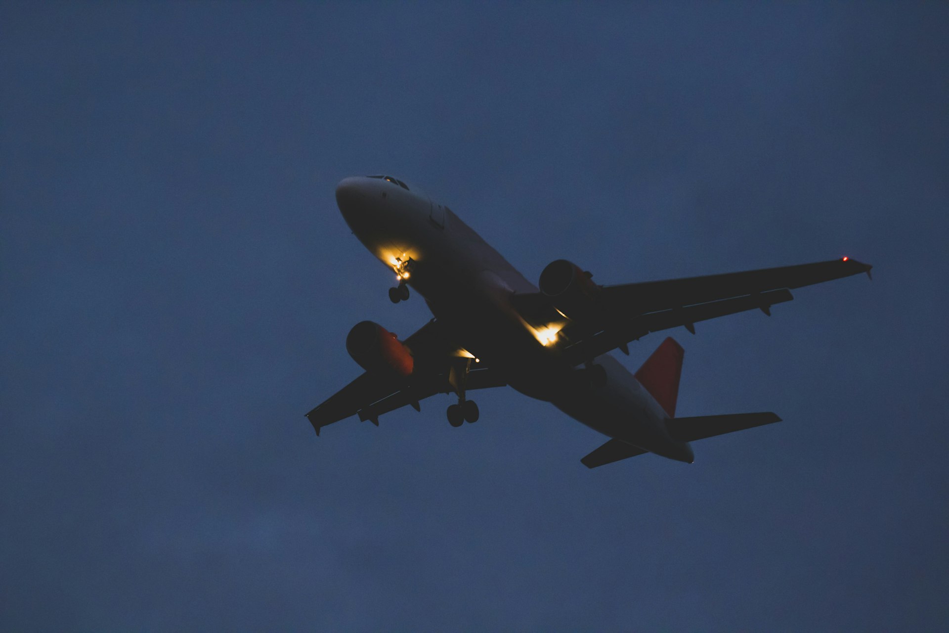 A passenger plane flies through a dark sky at dusk