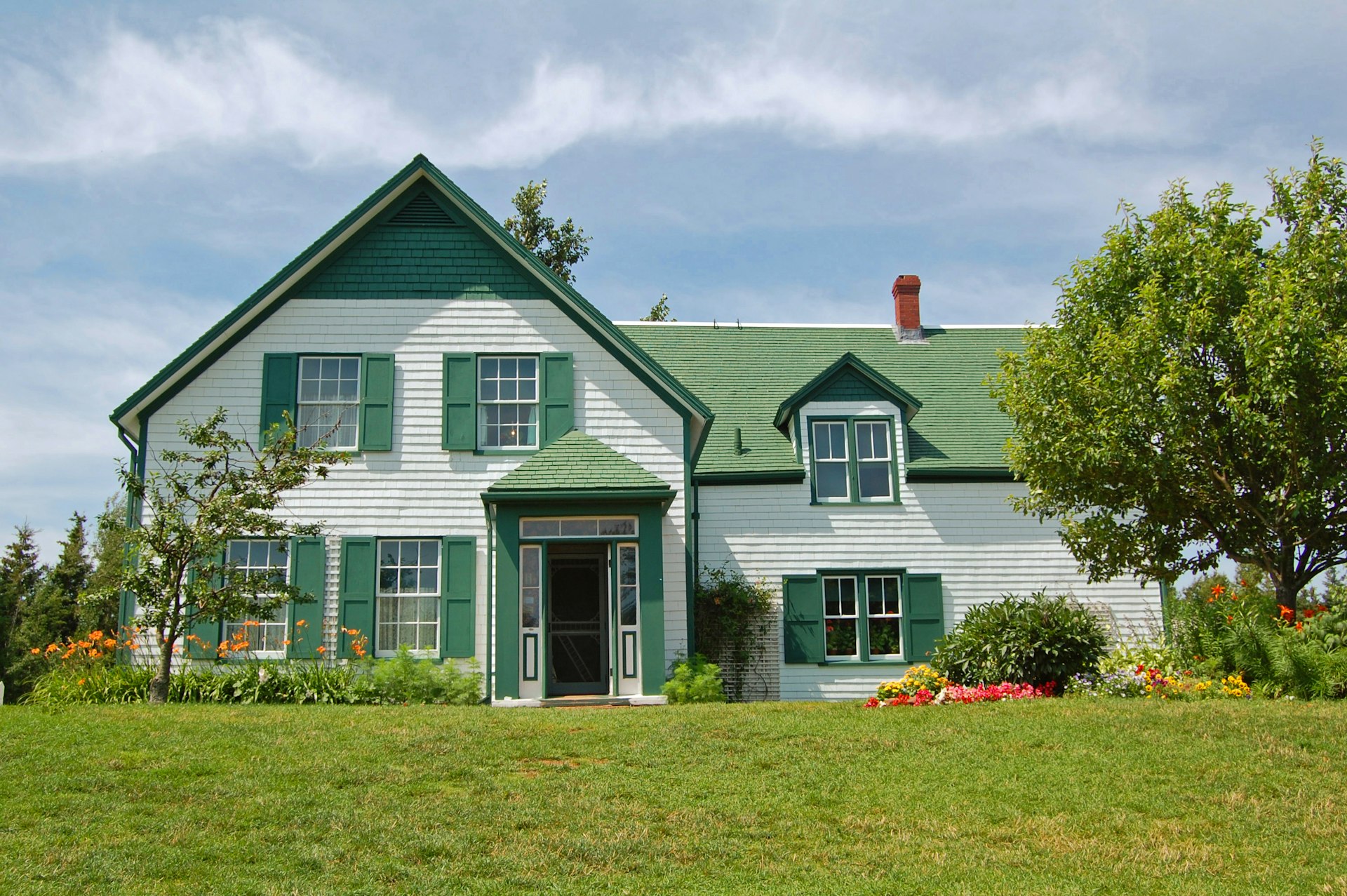 A white and green house with flowers outside