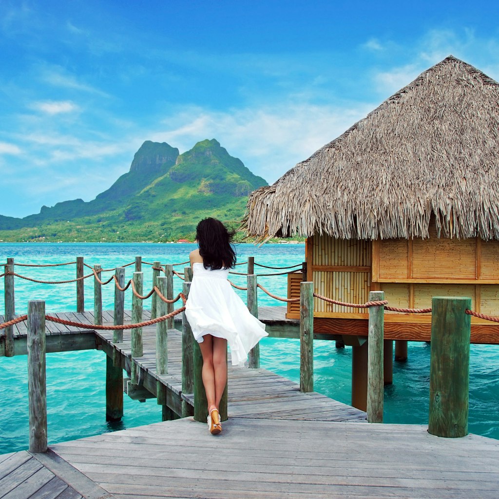  Young lady stand alone , look towards to the Otemanu mountain at Bora Bora island , French Polynesia , Pacific ocean .