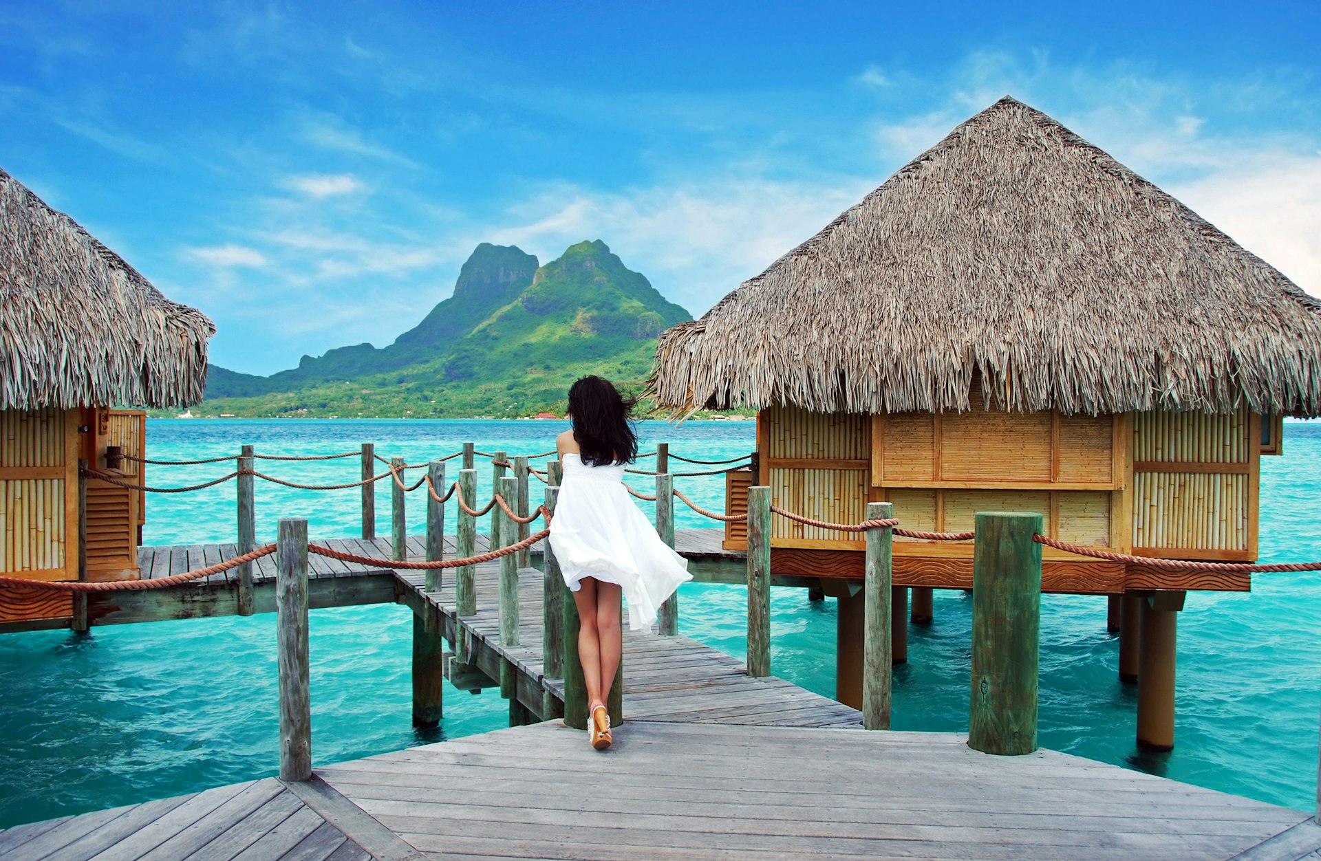 A woman looks from overwater bungalows to the mountains on Bora Bora